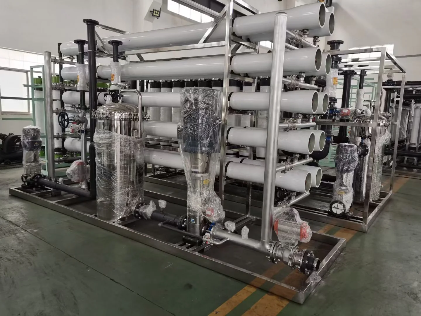 Industrial reverse osmosis treatment skid with pressure vessels and pumps